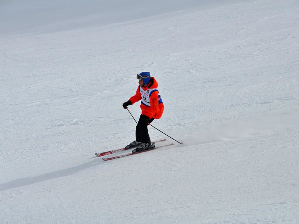 Skifahrer im roten Anorak in der Kurve.
